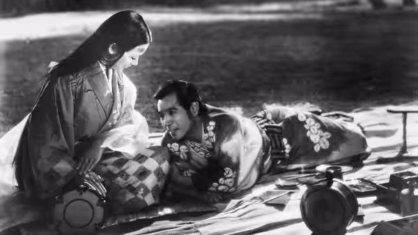 Lady Wakasa (Machiko Kyō) sits beside Genjurô (Masayuki Mori) reclining among cushions