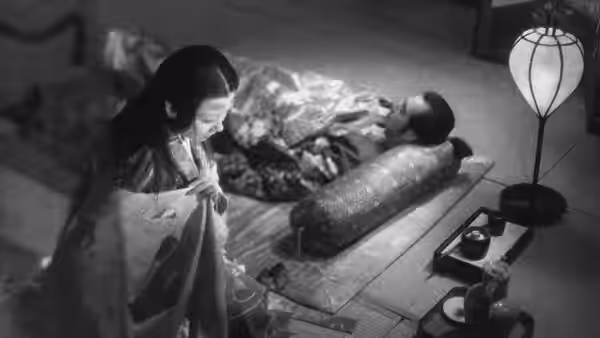 Lady Wakasa (Machiko Kyō) looks down at a man lying beneath a coverlet