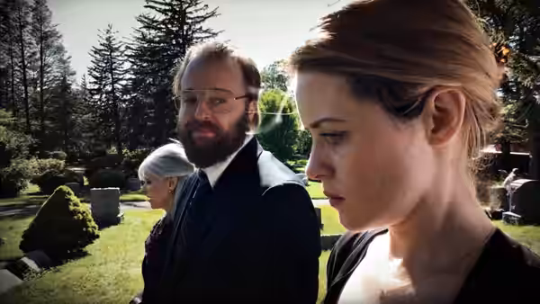 Sawyer Valentini (Claire Foy) standing outdoors beside a bearded man in a suit