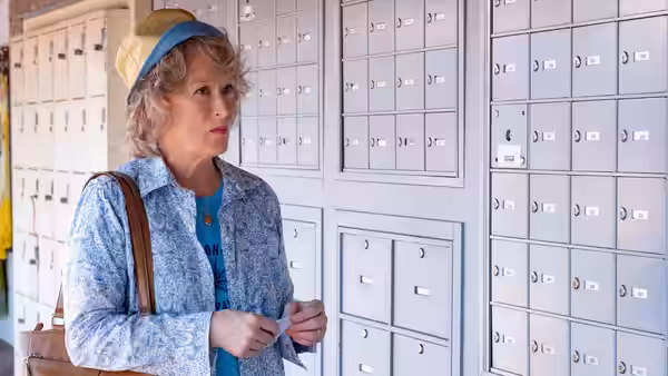 Ellen Martin (Meryl Streep) standing by rows of post office mailboxes