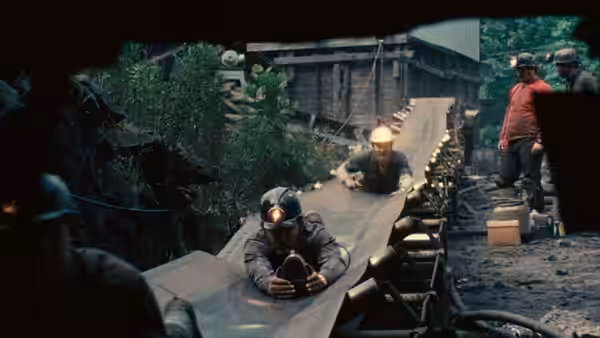 miners with headlamps working along a conveyor belt inside a mine tunnel