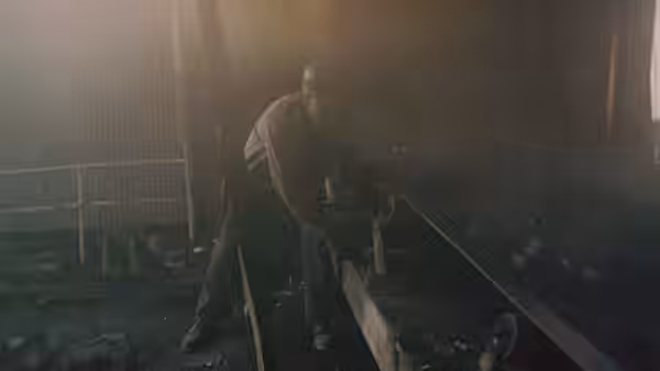 a miner in a hard hat working on machinery in a dark industrial space