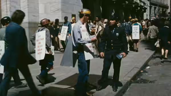 a police officer speaking with a man holding a sign during a street protest
