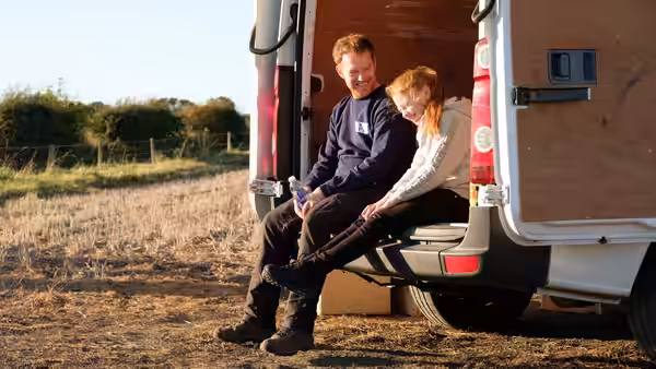 Ricky (Kris Hitchen) and Liza Jane (Katie Proctor) sit together at the open rear of the van