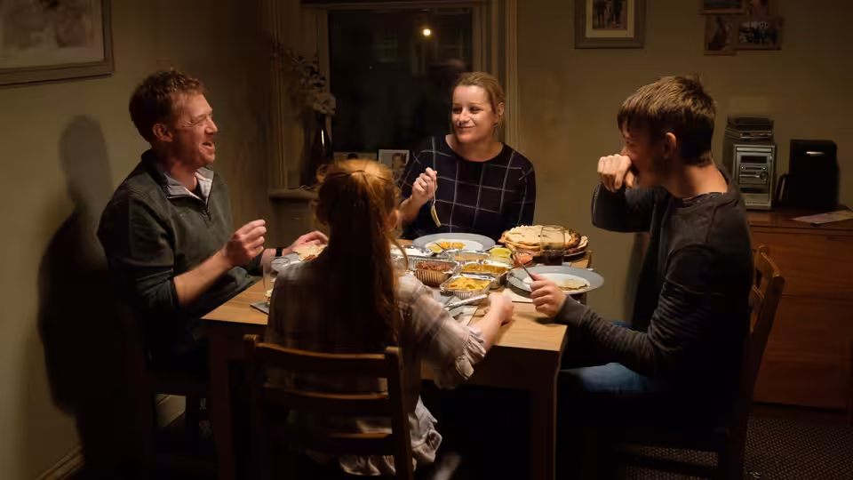 Ricky (Kris Hitchen), Abby (Debbie Honeywood), and their children share a meal around the dining table