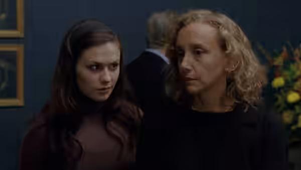 Young woman and older blonde woman stand side by side looking to the right