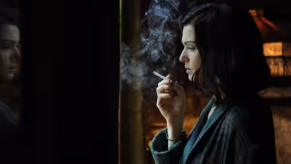 Hester Collyer (Rachel Weisz) smokes a cigarette while looking to her left
