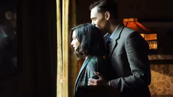Freddie Page (Tom Hiddleston) stands behind Hester Collyer (Rachel Weisz) at a window