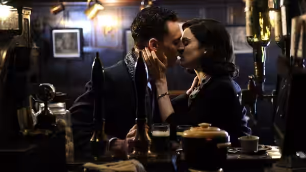 Hester Collyer (Rachel Weisz) and Freddie Page (Tom Hiddleston) kiss at a bar table