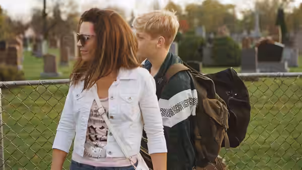 Diane (Anne Dorval) walking beside Steve near a cemetery fence