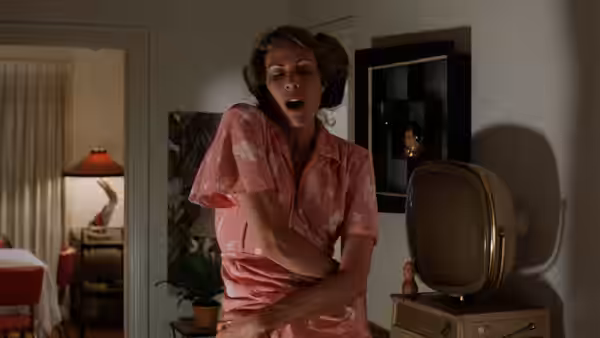 Mary Bland (Mary Woronov) in pink pajamas clutching her chest in shock