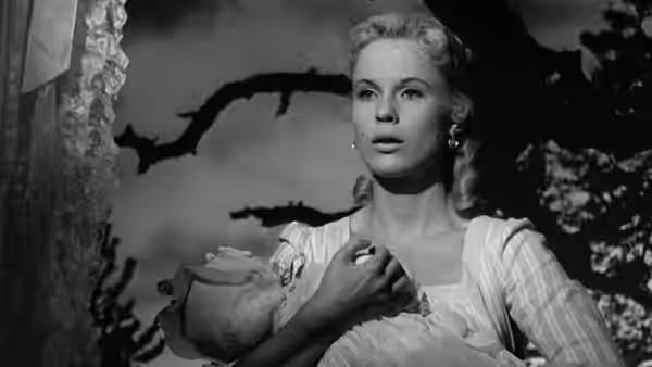 Sara (Bibi Andersson) stands outdoors holding a bundle against her chest