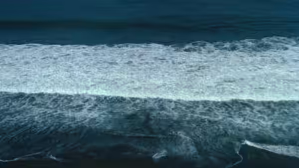 Waves breaking with white foam across dark blue ocean water