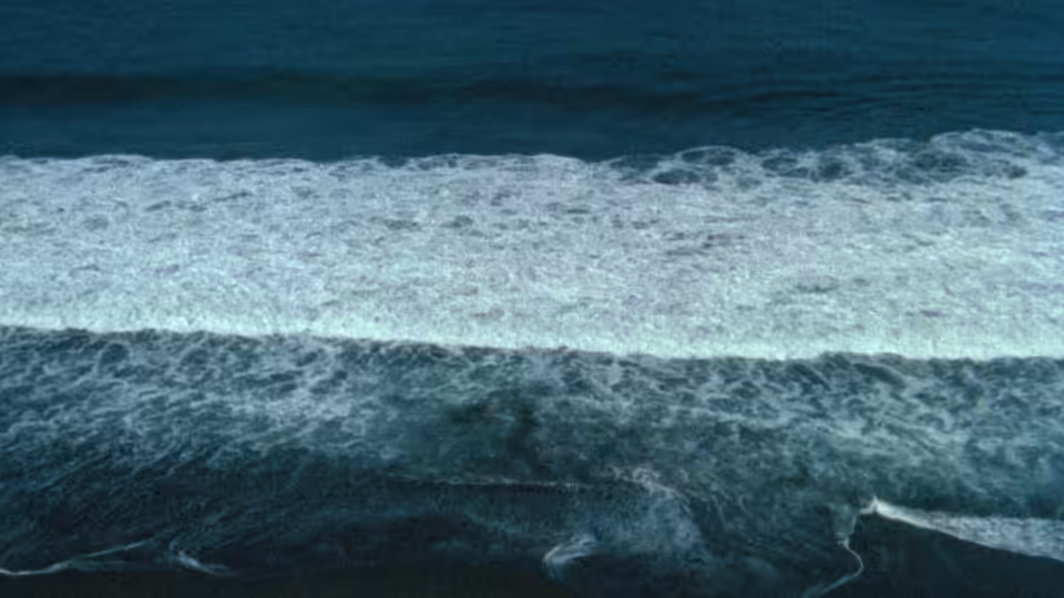 Waves breaking with white foam across dark blue ocean water