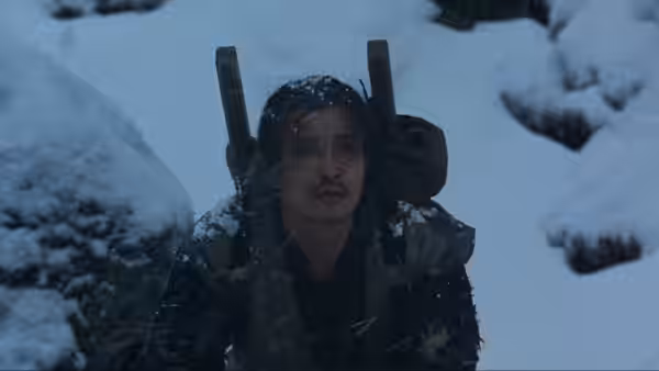 Tatsuhei (Ken Ogata) standing in falling snow with poles strapped to his back
