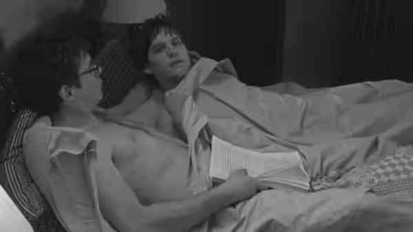 James Leer (Tobey Maguire) in bed holding a manuscript while another man watches