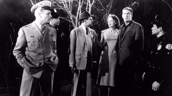 A group of men and a woman stand together outdoors at night