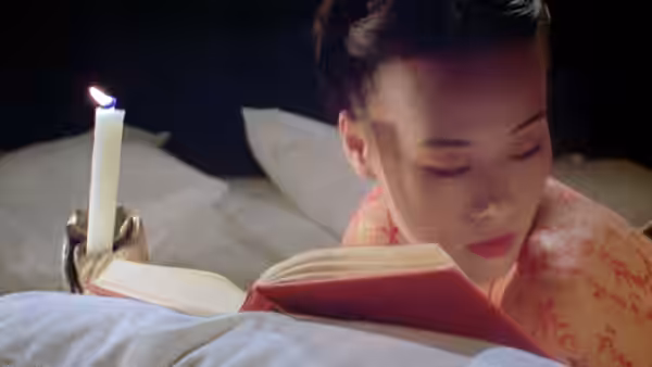 Nagiko (Vivian Wu) reads an open book beside a candle