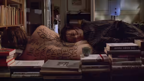 A man lies asleep among piles of books while a woman stands in the doorway