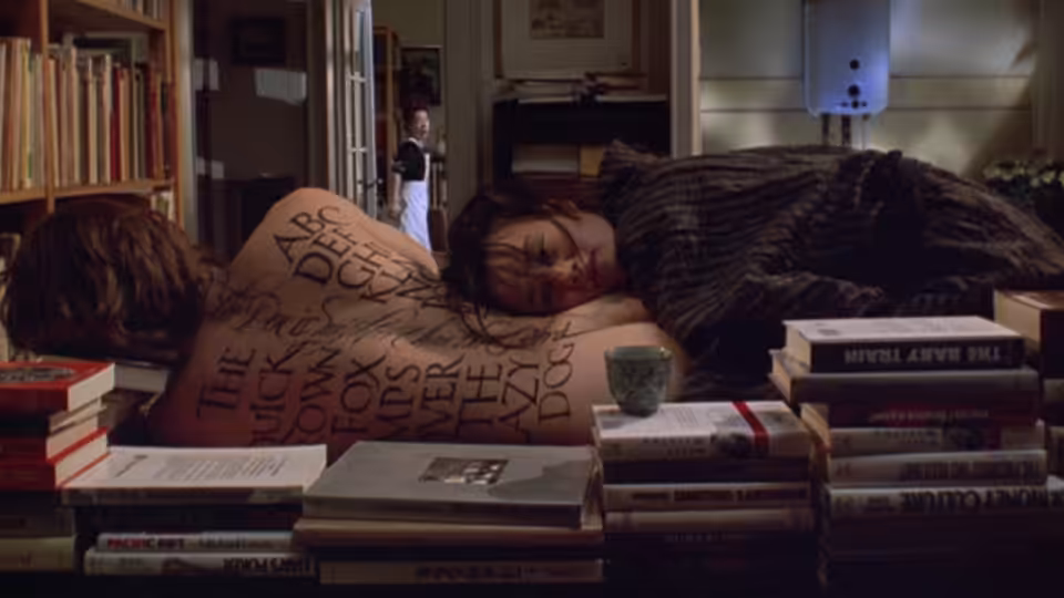 A man lies asleep among piles of books while a woman stands in the doorway