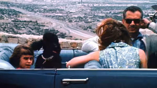 Michael drives a blue convertible with his family and dog