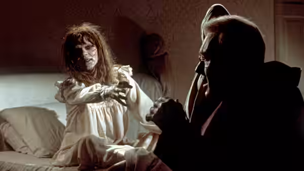 Regan (Linda Blair) in a white nightgown reaches toward Father Lamont (Richard Burton)