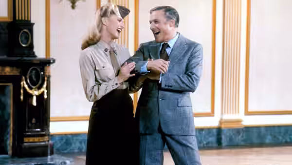 Kira (Olivia Newton-John) and Danny McGuire (Gene Kelly) laughing together in a grand hall
