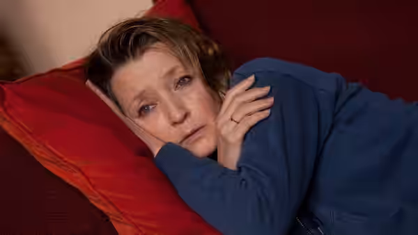 Mary lying on a red sofa with a worried expression