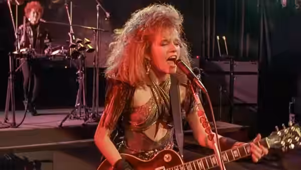 Beverly Switzler (Lea Thompson) plays guitar and sings on stage