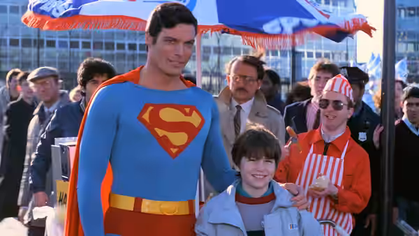 Superman (Christopher Reeve) poses with a boy and hot dog vendor outdoors