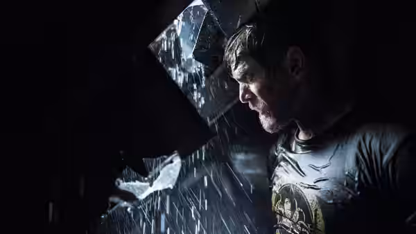 Dave (Barry Pepper) peers through a broken opening as rain pours into the house
