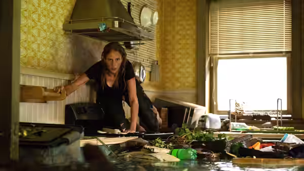 Haley (Kaya Scodelario) braces herself in a flooded kitchen amid floating debris