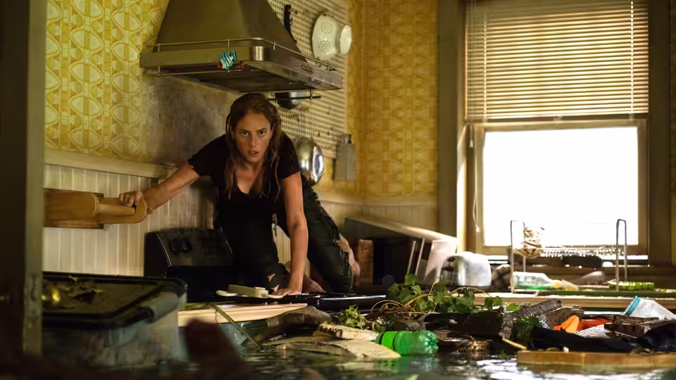 Haley (Kaya Scodelario) braces herself in a flooded kitchen amid floating debris