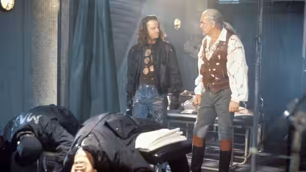 Two men standing over fallen figures in a cluttered interior room