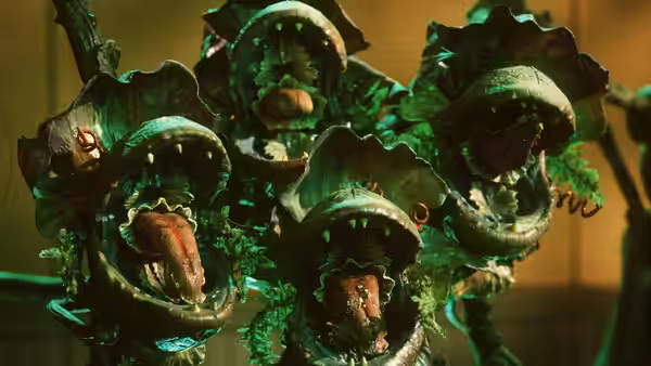 Cluster of small green plants with open mouths and red tongues