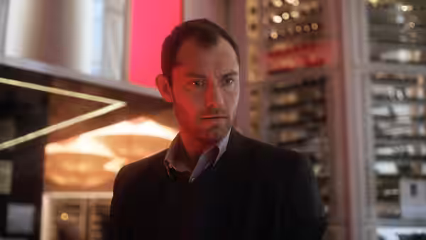 Jonathan Banks (Jude Law) standing with a concerned expression indoors