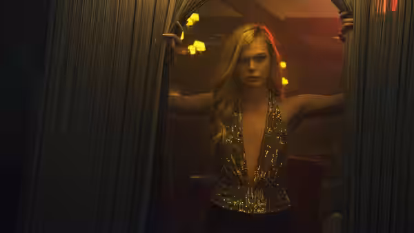 Jesse (Elle Fanning) stands in a dim doorway