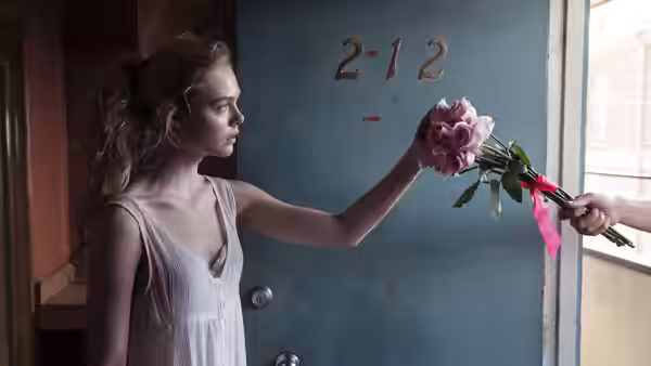 Jesse (Elle Fanning) reaches for a bouquet offered through a doorway