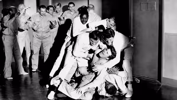 Hospital patients and attendants pile together on the floor in a corridor
