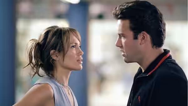 Ricki (Jennifer Lopez) and Larry (Ben Affleck) standing face to face indoors