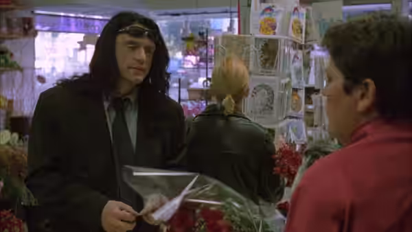 Johnny (Tommy Wiseau) holding flowers while speaking in a shop