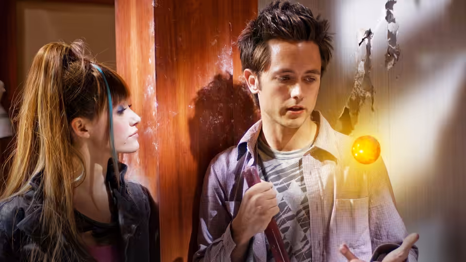 Goku (Justin Chatwin) holding a glowing orange sphere beside a woman with ponytail