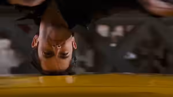 Goku (Justin Chatwin) hanging upside down above a yellow surface