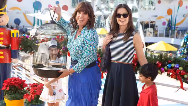 Two women and two children with a birdcage at an outdoor market