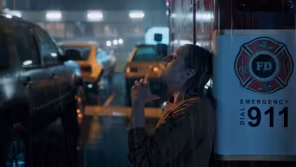Cecilia Kass (Elisabeth Moss) leans against an emergency call box in the rain