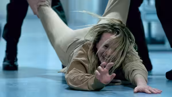 Cecilia Kass (Elisabeth Moss) reaches across the floor as someone pulls her by the arm