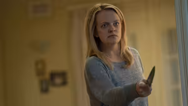Cecilia Kass (Elisabeth Moss) grips a knife inside a home