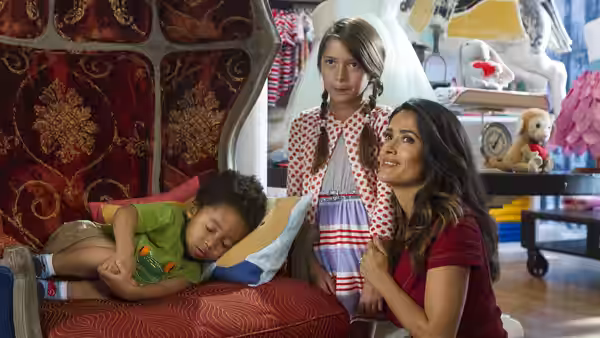 Roxanne Chase-Feder (Salma Hayek) sits with children in a playroom one asleep