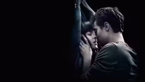 Anastasia Steele (Dakota Johnson) and Christian Grey (Jamie Dornan) embracing in a dark space