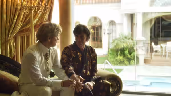 Liberace (Michael Douglas) and Scott Thorson (Matt Damon) conversing on a couch